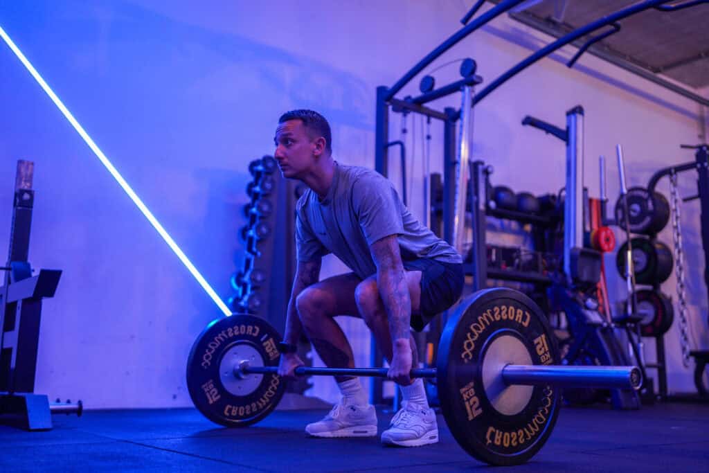 Een man staat in de startpositie van een trap bar deadlift in de gym.